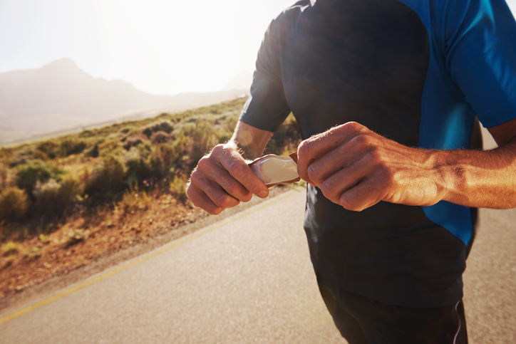Mann öffnet Energy Gel während Lauf